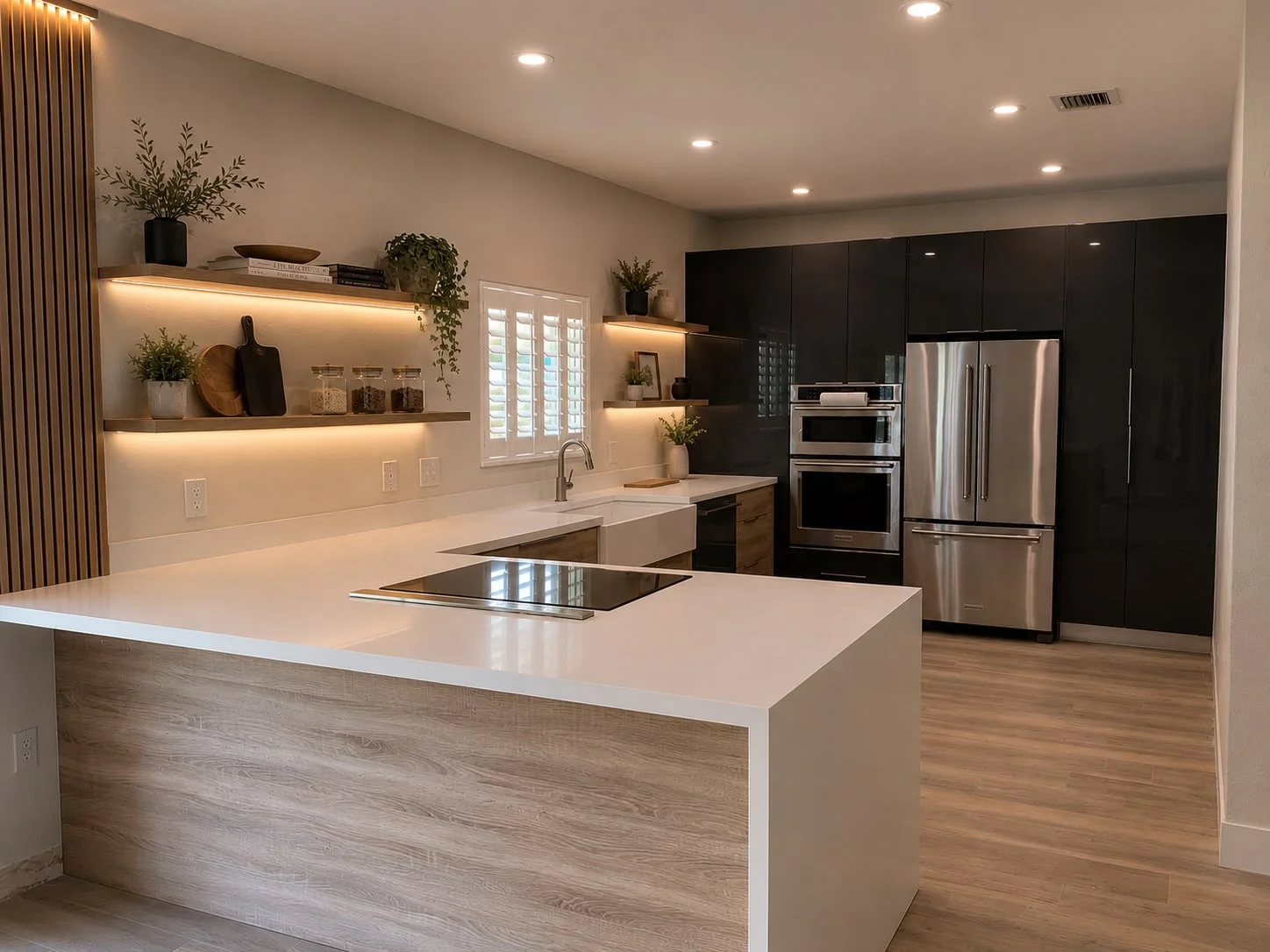 Modern kitchen with warm wood-tone flooring, white island countertop, and black cabinetry
