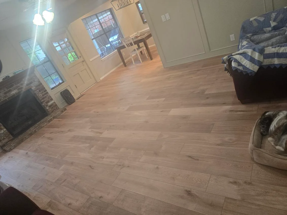Light oak hardwood flooring installed in open living room with furniture and windows