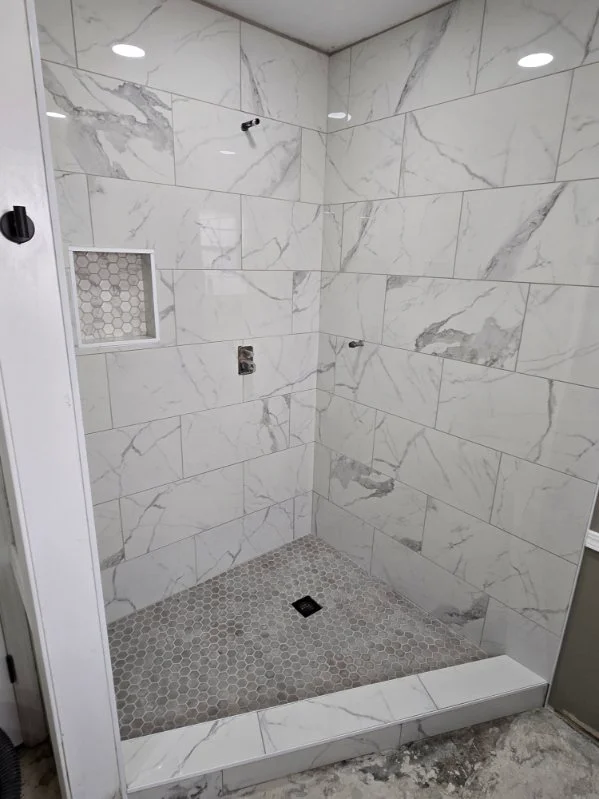 Modern shower with marble tile walls and hexagonal floor tile in gray and white