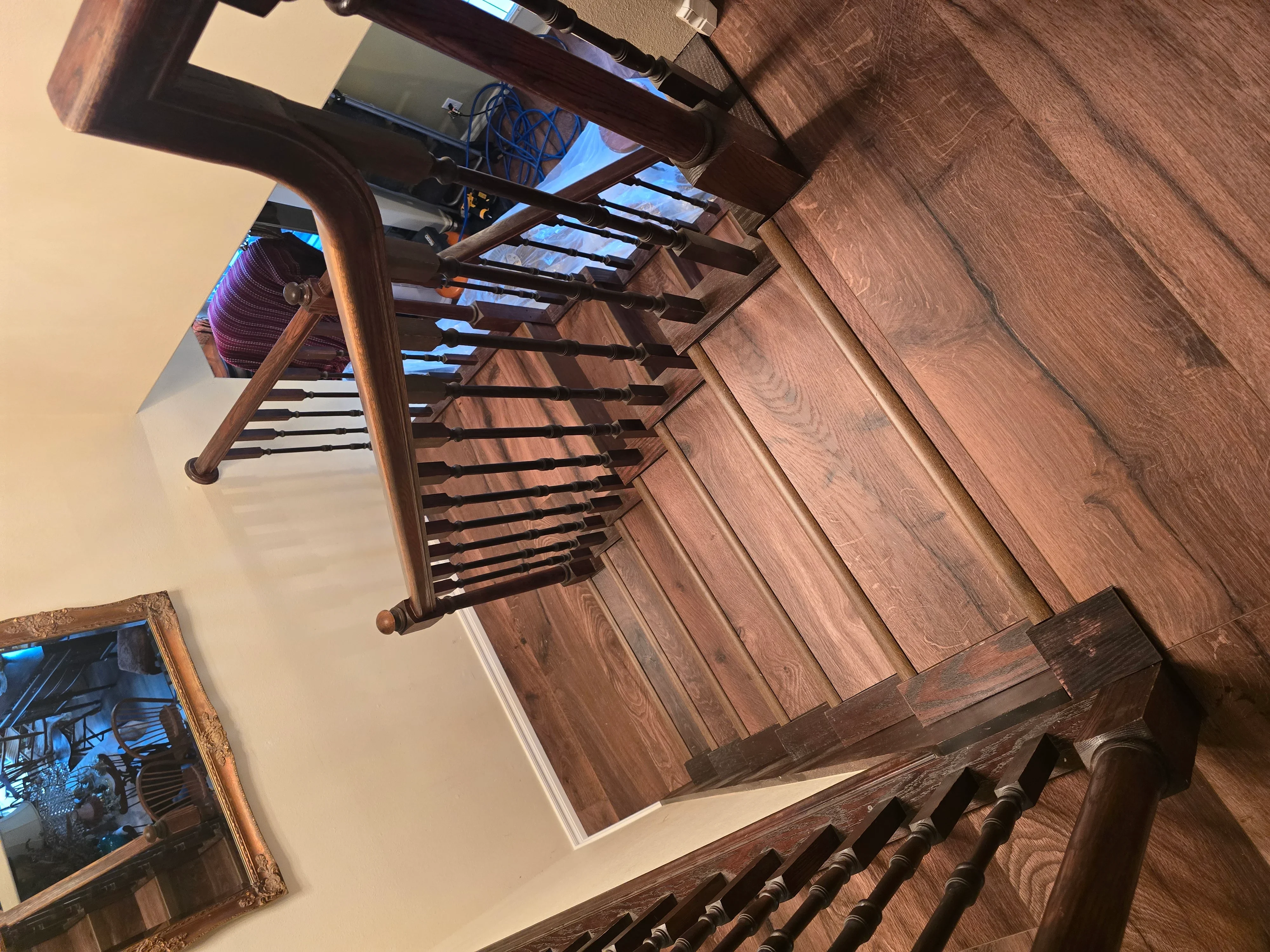 Hardwood flooring with custom wooden staircase featuring walnut tones and turned balusters