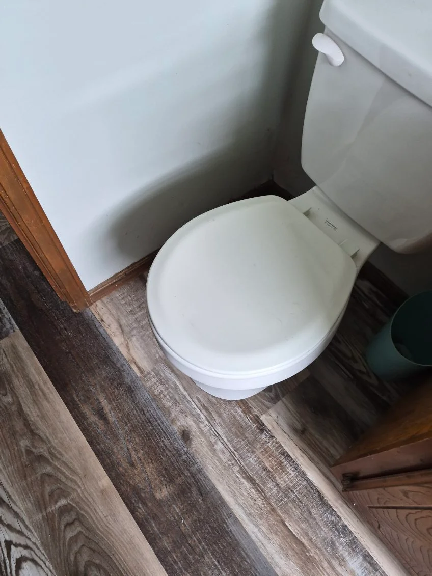 Bathroom with new wood-look vinyl plank flooring and white tile walls