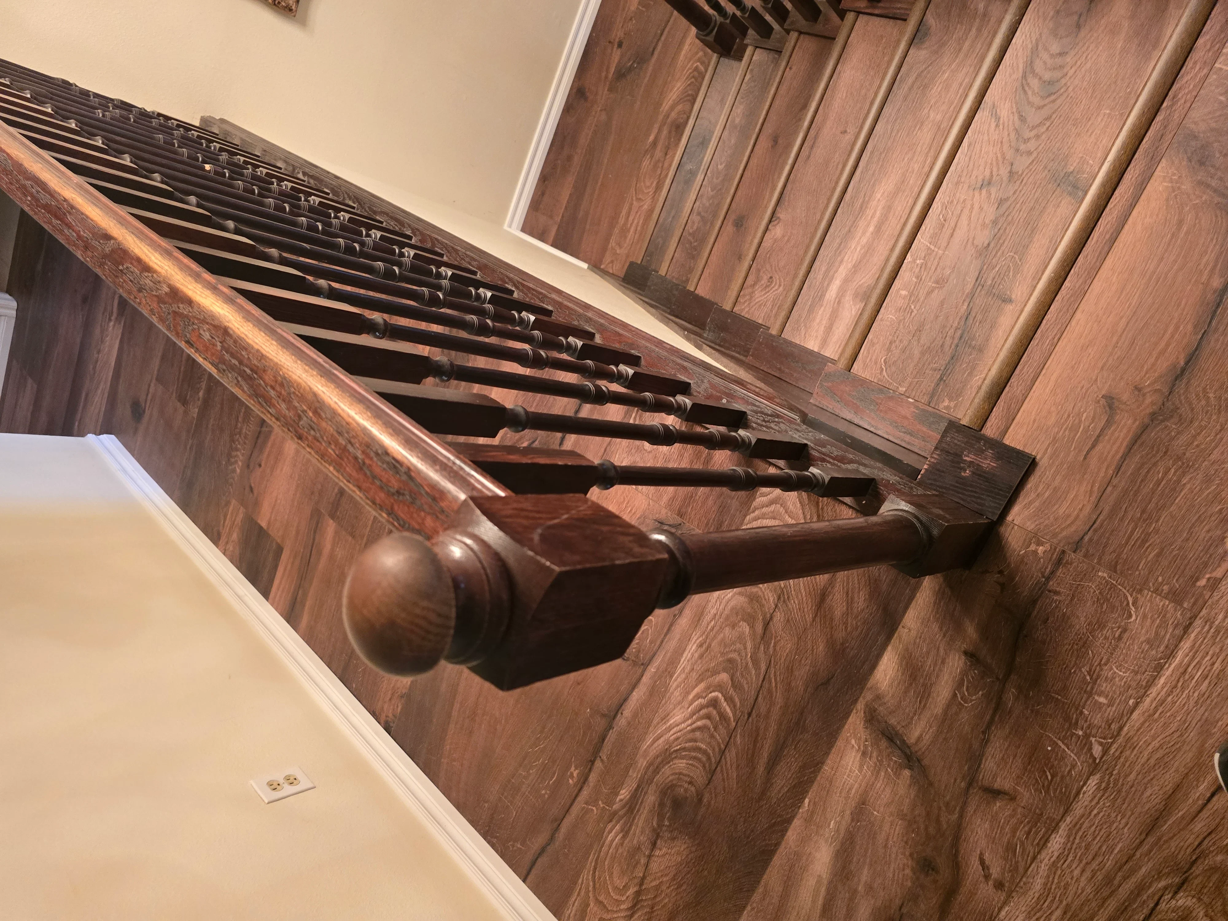 Wooden staircase with walnut-toned hardwood flooring and turned spindles