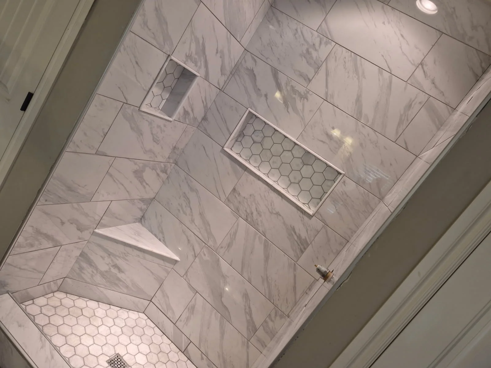 Overhead view of marble tile shower with hexagonal accent tiles and subway tile layout