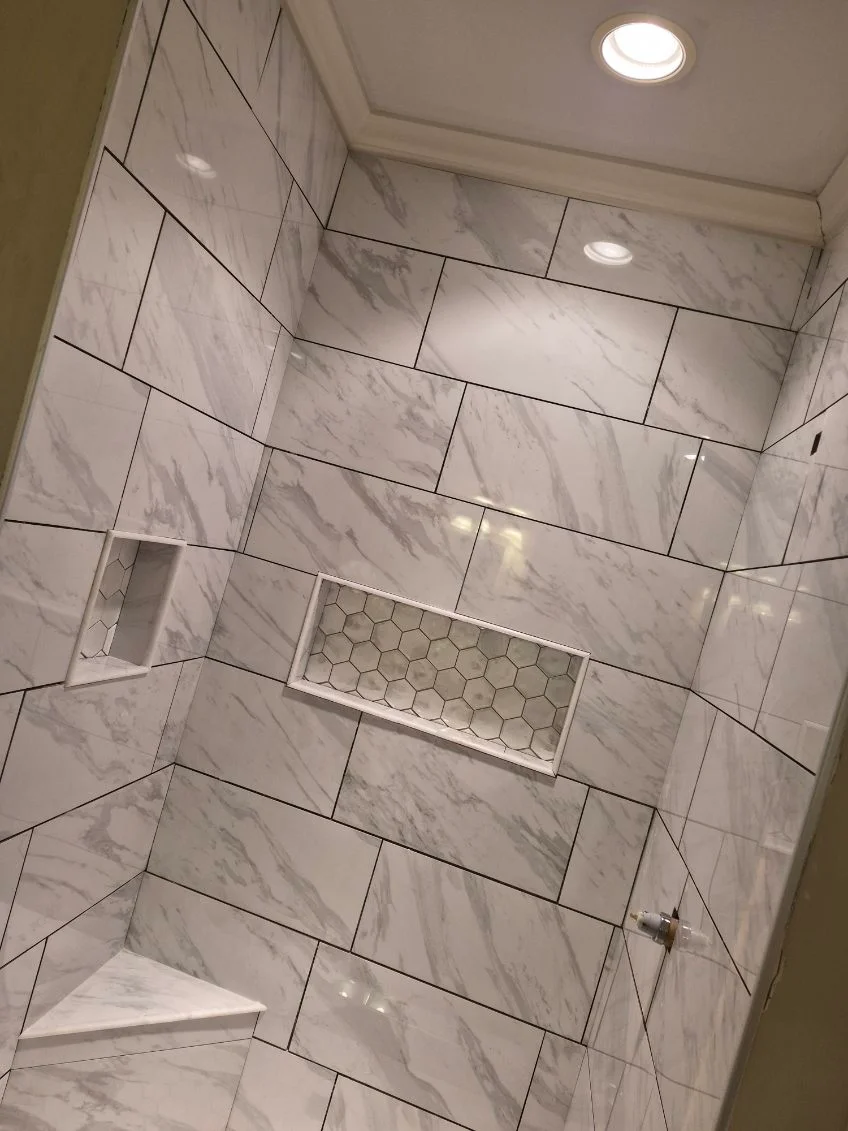 Marble subway tile shower with staggered pattern, recessed niche, and recessed lighting
